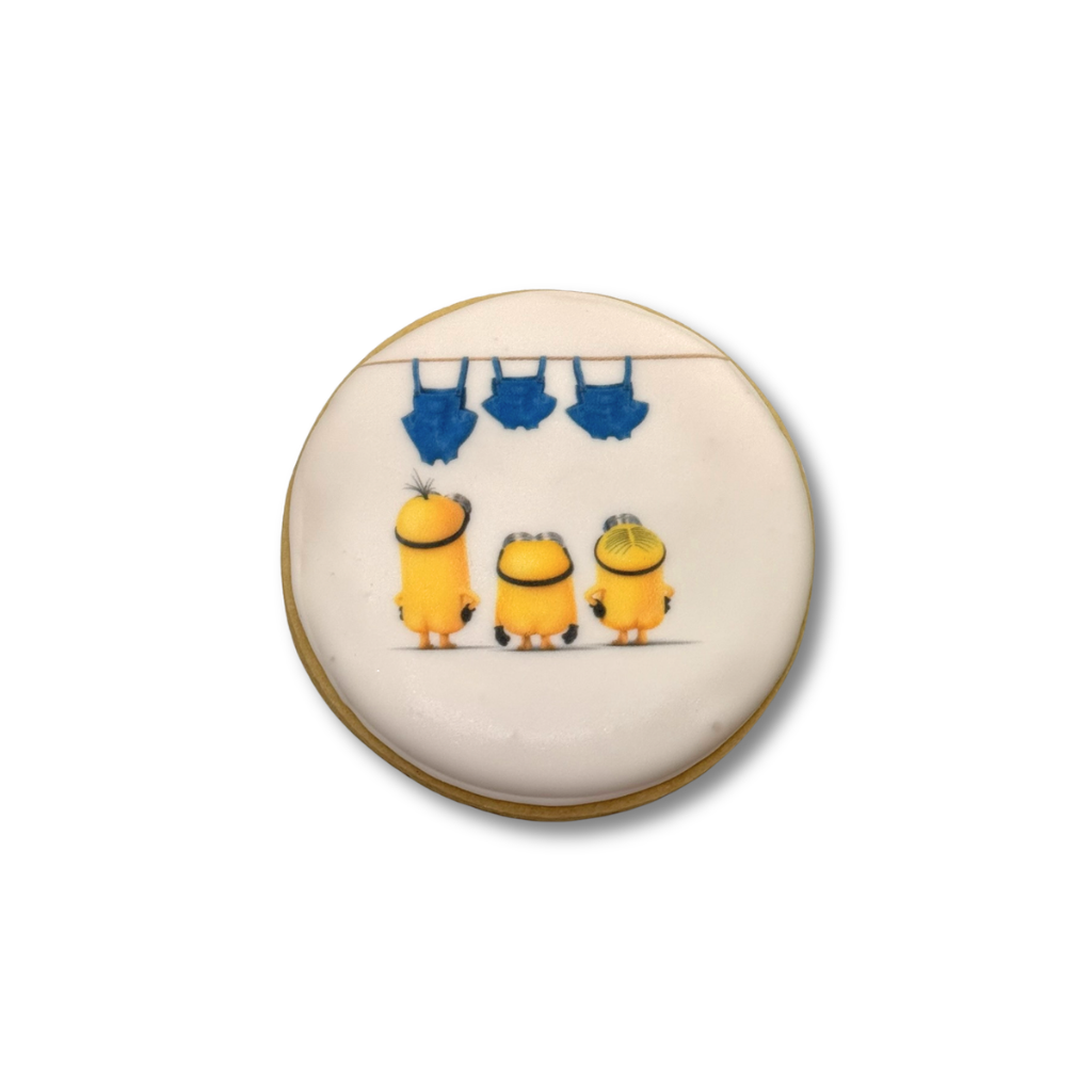 Round Minions cookie with three characters and blue overalls.
