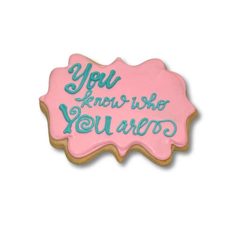 Moana cookie with pink icing and teal cursive lettering.