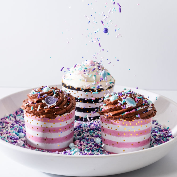 Assorted cupcakes with sprinkles in a white bowl.