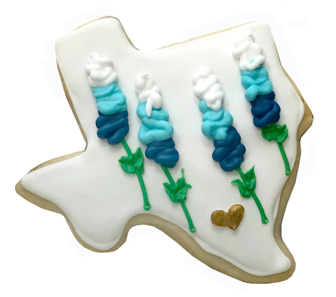 Texas-shaped cookie decorated with bluebonnets and a gold heart.