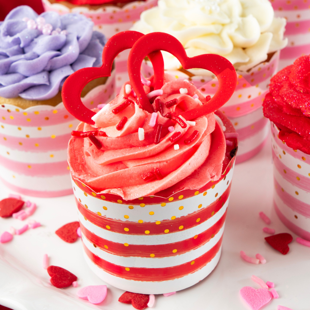 Valentine cupcakes with pink frosting and red heart toppers.