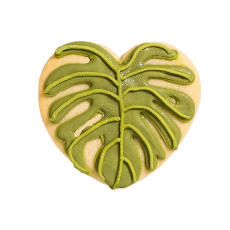 Heart-shaped cookie with green monstera leaf icing.