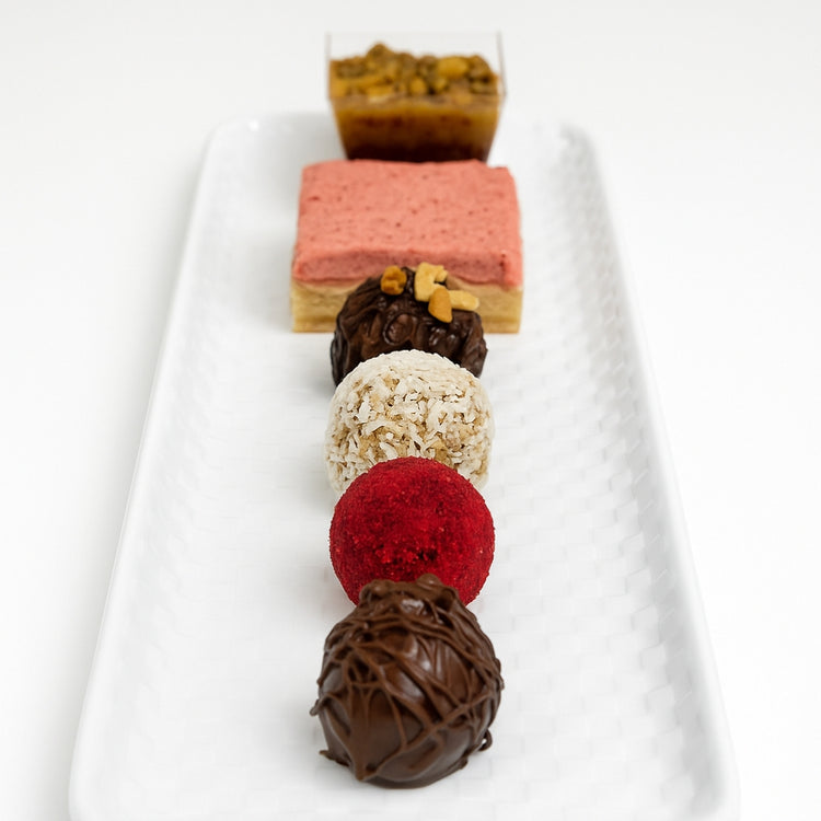 Raspberry Sweet Tarts and assorted truffles on a white tray.
