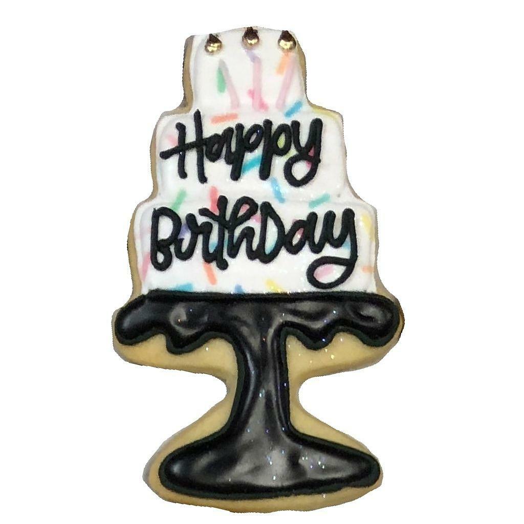 Birthday cake cookie on a black stand with colorful sprinkles