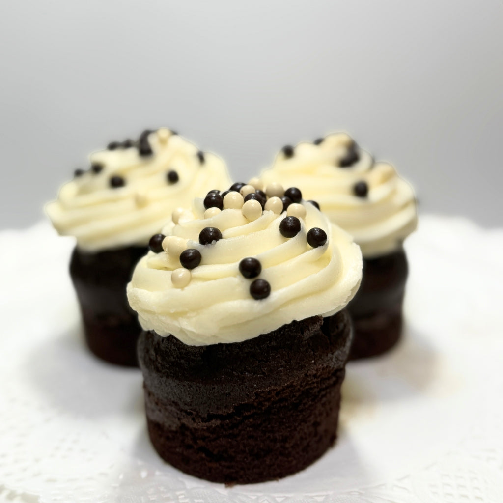 Three chocolate cupcakes with vanilla frosting and sprinkles.