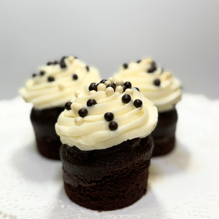 Three chocolate cupcakes with vanilla frosting and sprinkles.