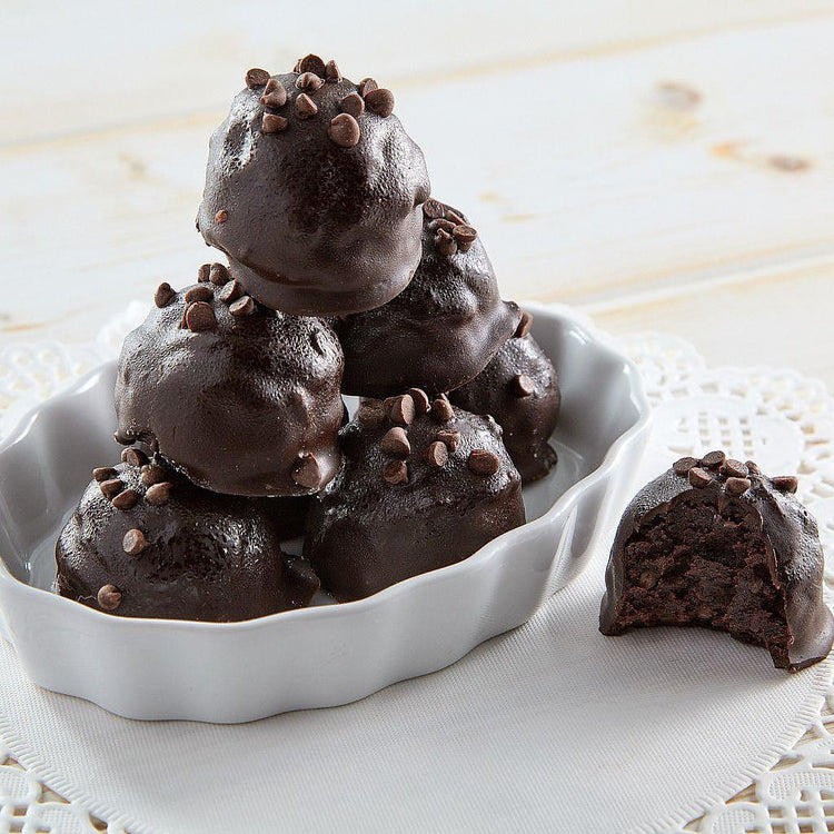 Chocolate chip cake balls stacked in a white ceramic dish.
