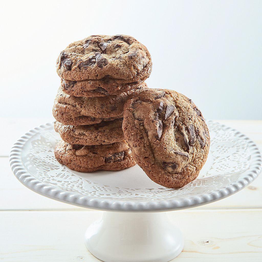 Stack of chocolate chunk cookies on a white pedestal stand