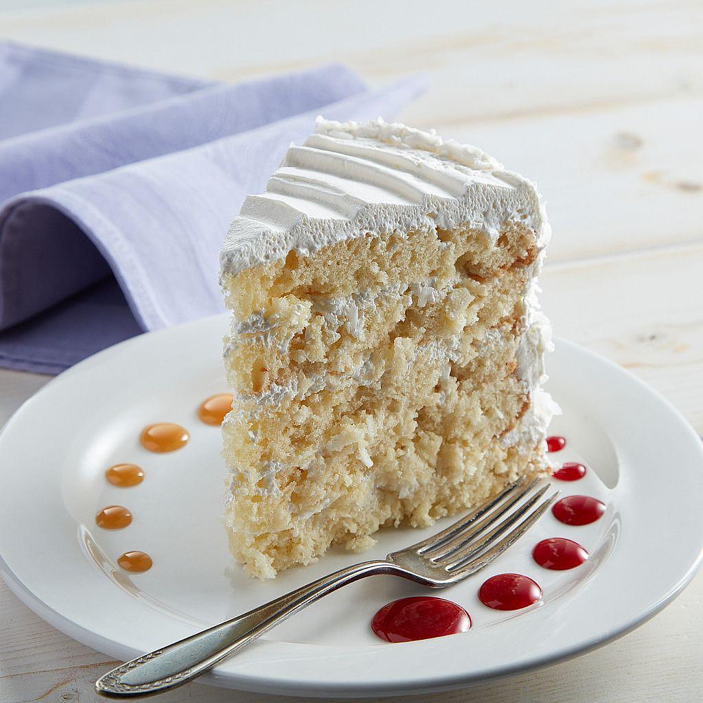 Slice of coconut cake with white frosting on a plate