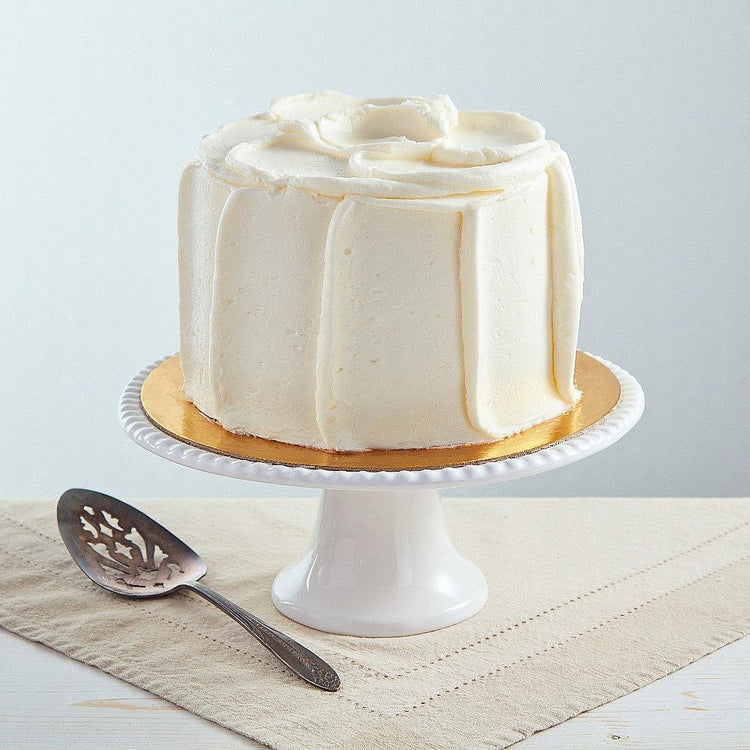 6-inch French vanilla cake with white frosting on a pedestal.