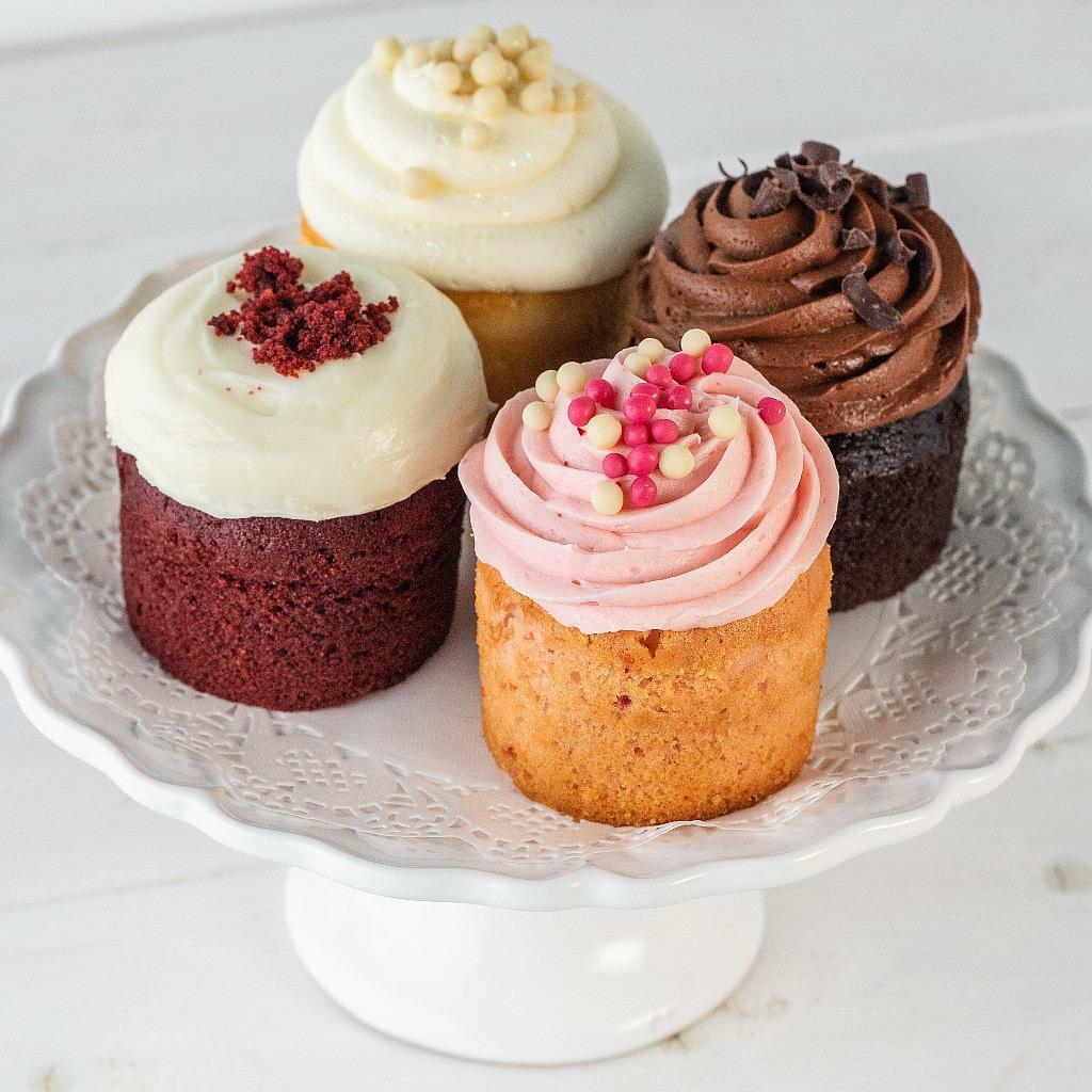 Four assorted chocolate cupcakes on a white pedestal stand.