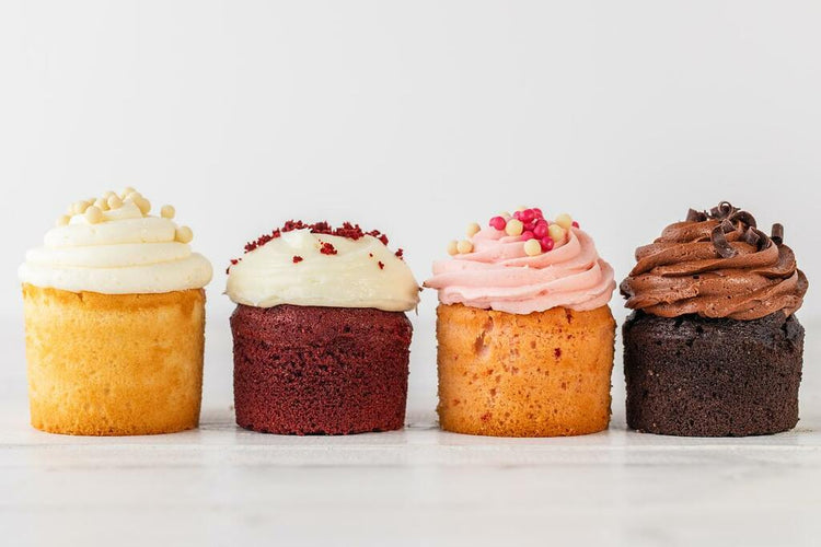 Four assorted strawberry and chocolate cupcakes in a row.
