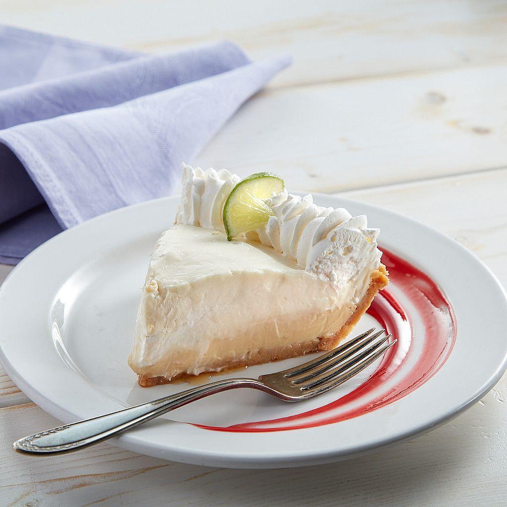 Slice of key lime pie with whipped cream on a white plate