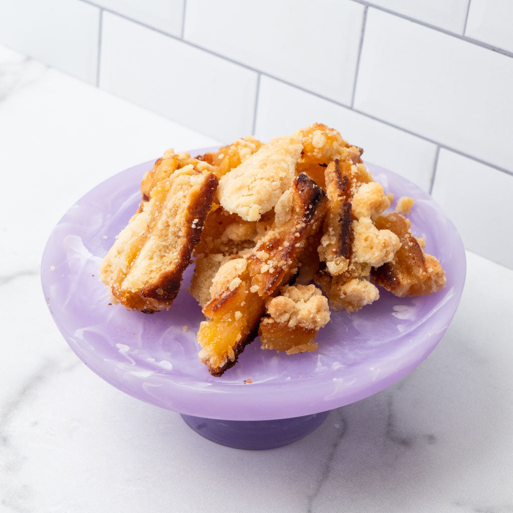 Edges pastry pieces on a purple pedestal stand