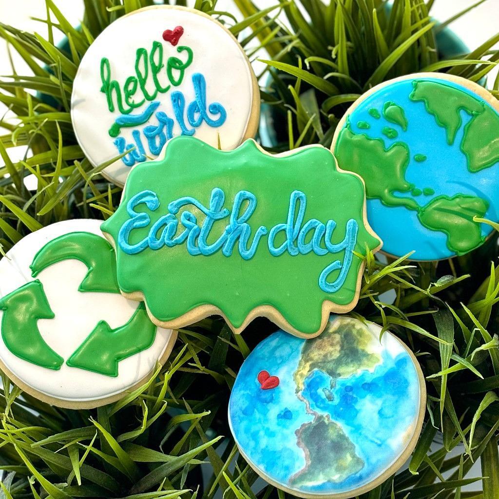 Assorted Earth Day cookies decorated with icing on green grass.
