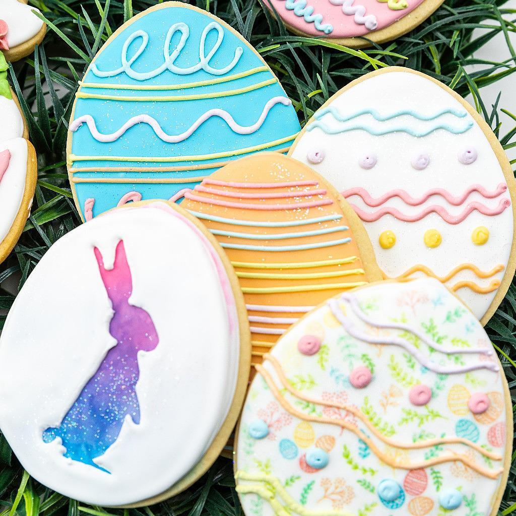 Easter 2025 egg-shaped cookies with colorful icing on grass.