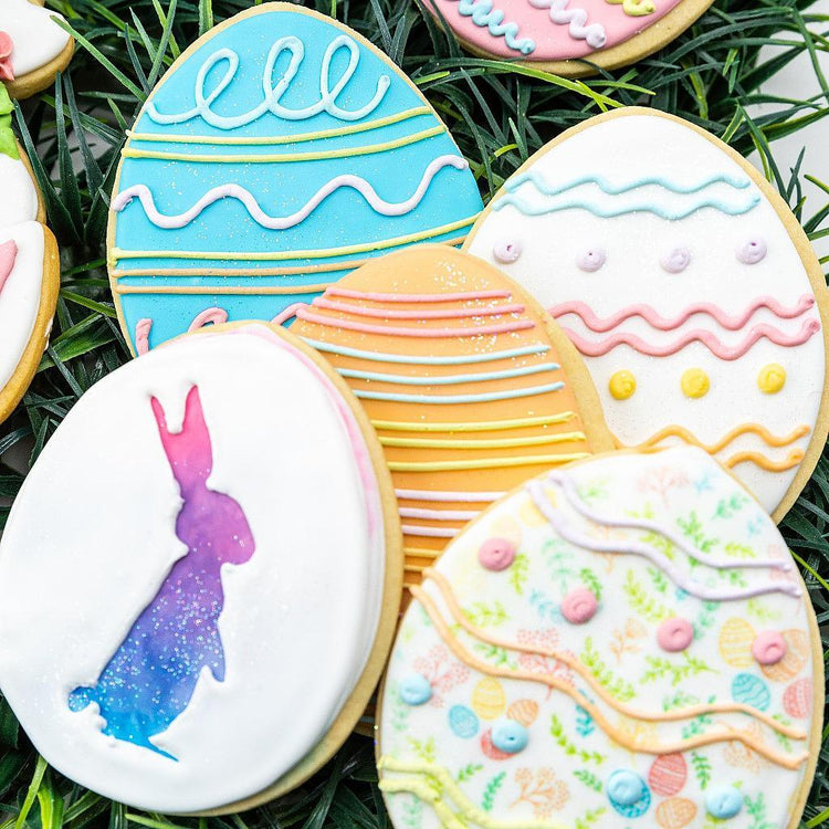 Easter 2025 egg-shaped cookies with colorful icing on grass.