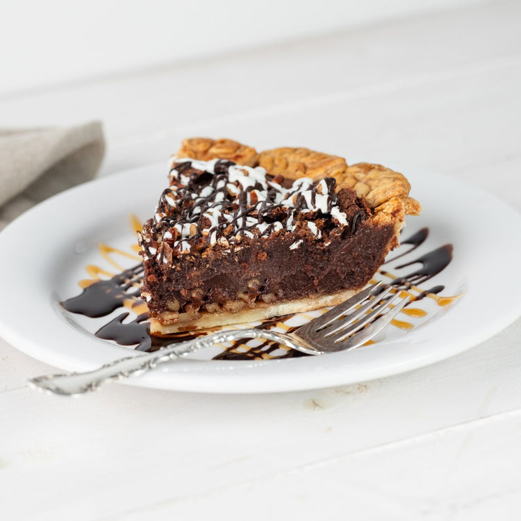 Slice of fudge pecan pie drizzled with chocolate on a plate