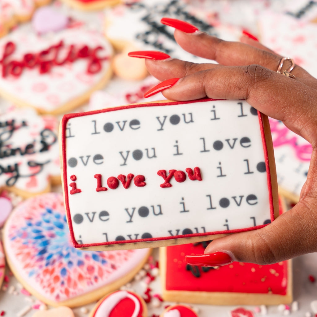 Rectangular I Love You cookie held by a hand with red nails