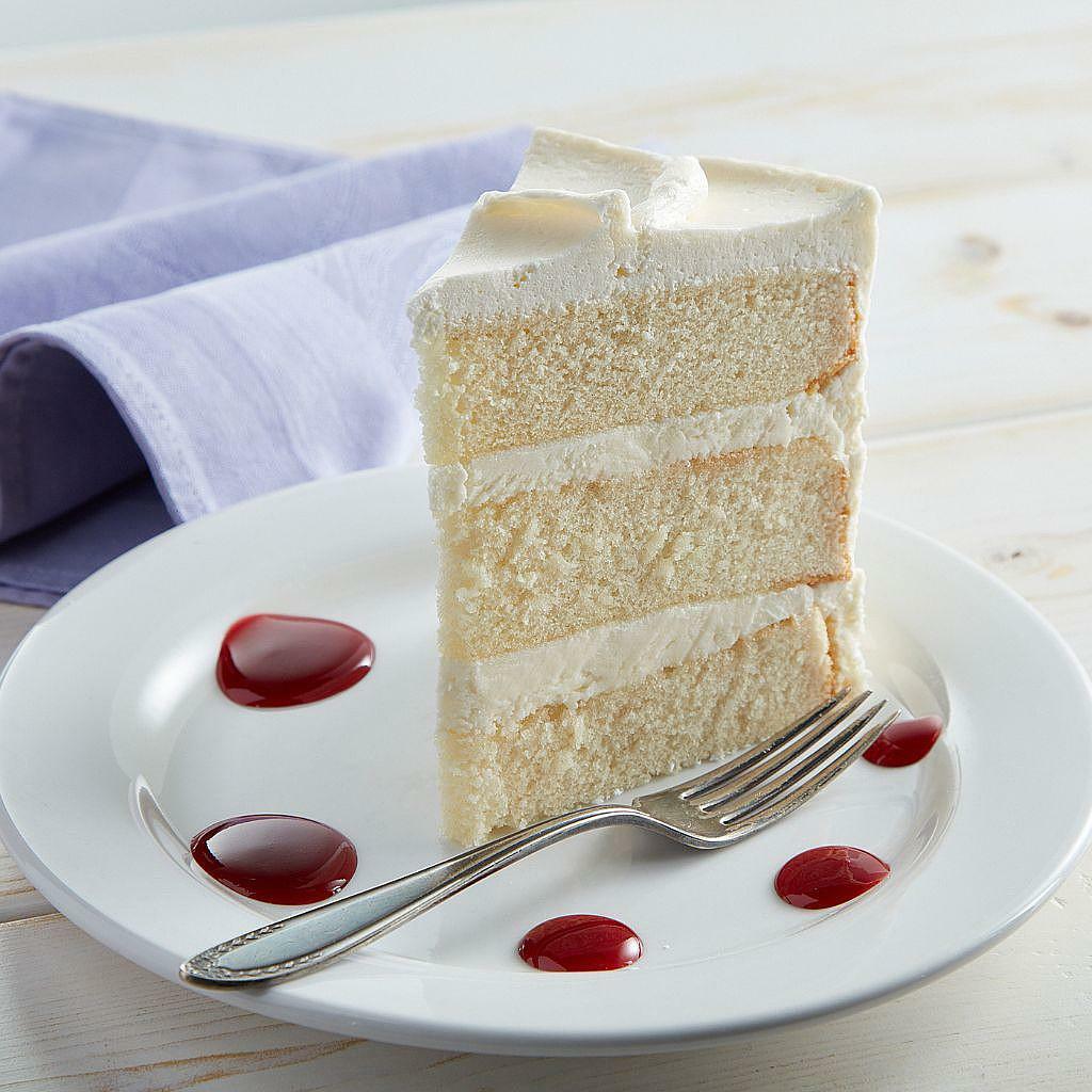 French Vanilla cake slice with frosting on a white plate.