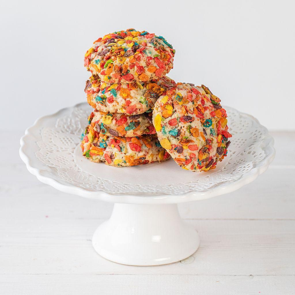 Stack of colorful Fruity Pebbles cookies on a white cake stand.