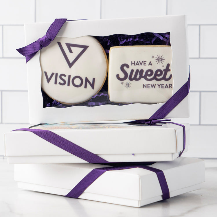 Two custom logo cookies in a white gift box with purple ribbon.