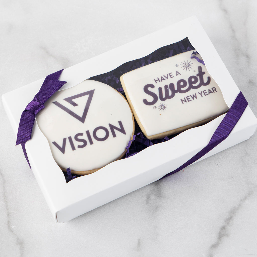 Two custom logo cookies in a white gift box with purple ribbon.