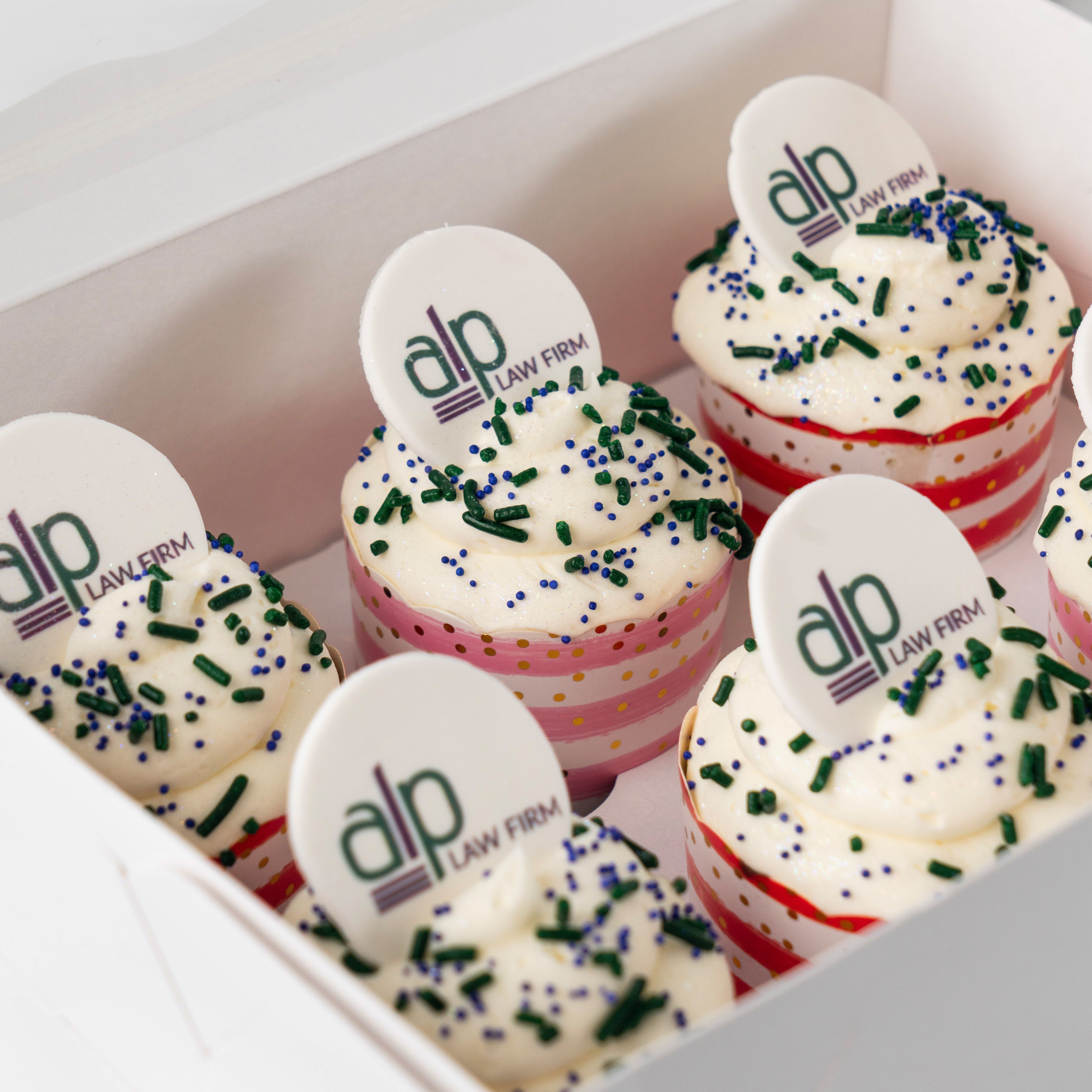 Photo & Logo cupcakes with blue and green sprinkles in a box.