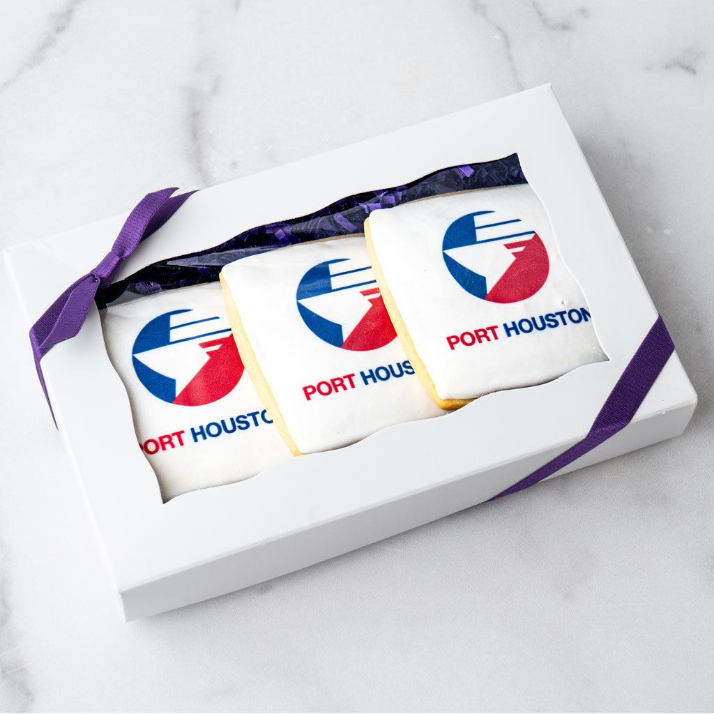 Three custom logo cookies in a white gift box with purple ribbon.