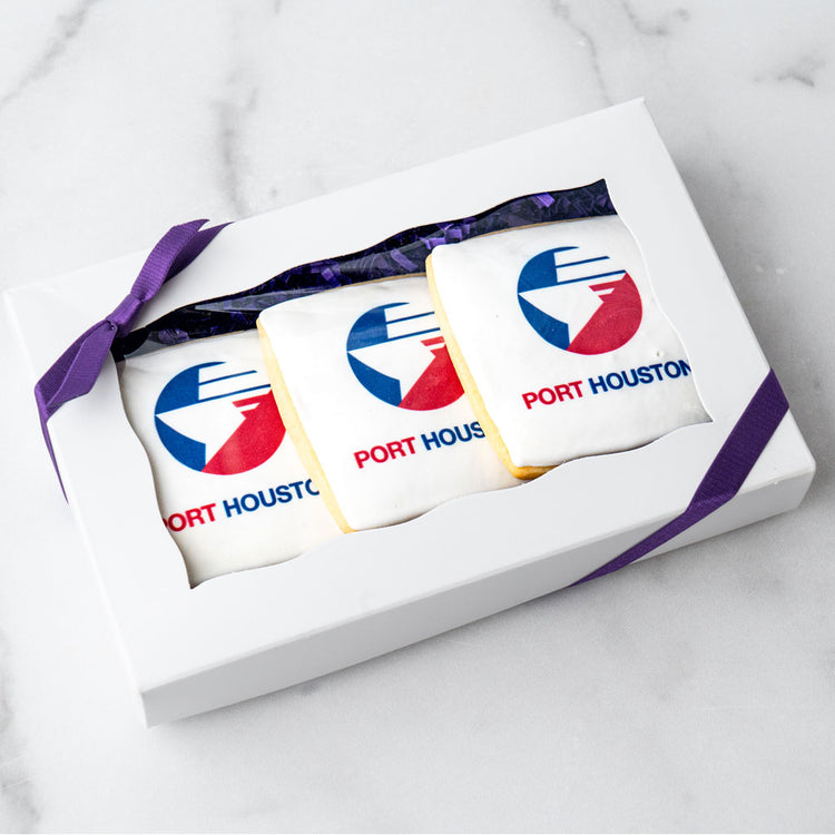 Three custom logo cookies in a white gift box with purple ribbon.