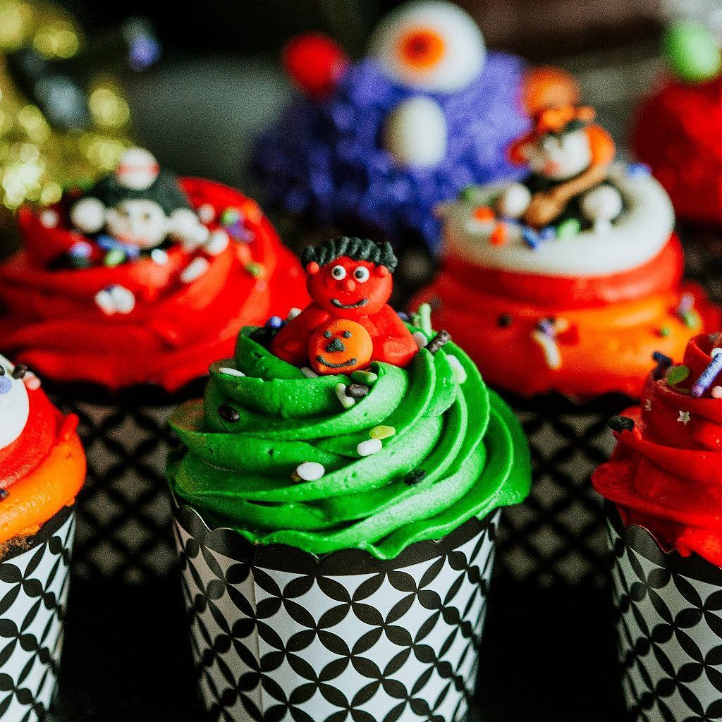 Halloween cupcakes with colorful frosting and monster toppers.