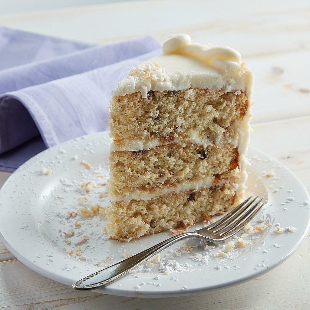 Italian Cream Cake slice with coconut frosting on a white plate.