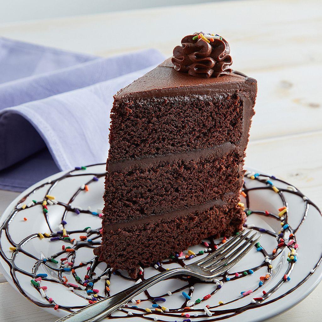 Slice of triple-layer chocolate cake with rainbow sprinkles