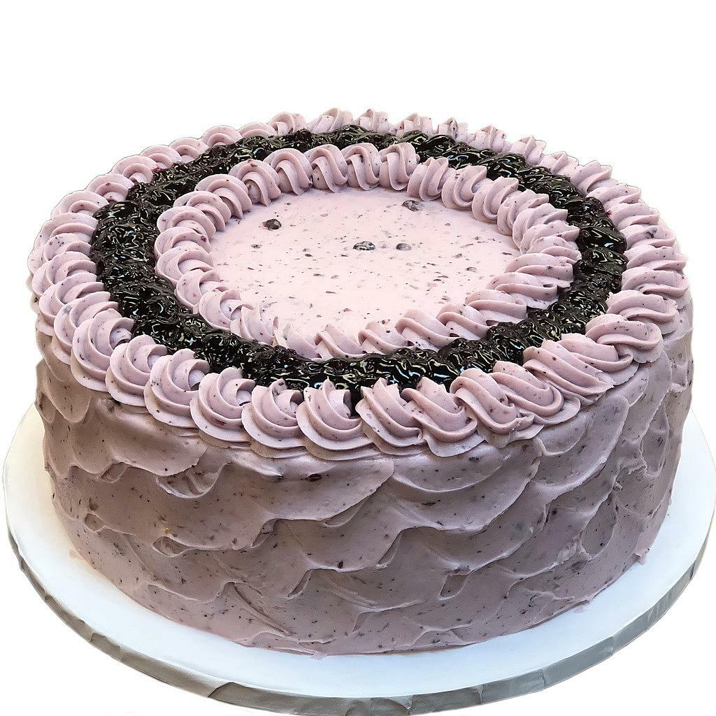 Round lemon blueberry cake with purple frosting and berry swirl.