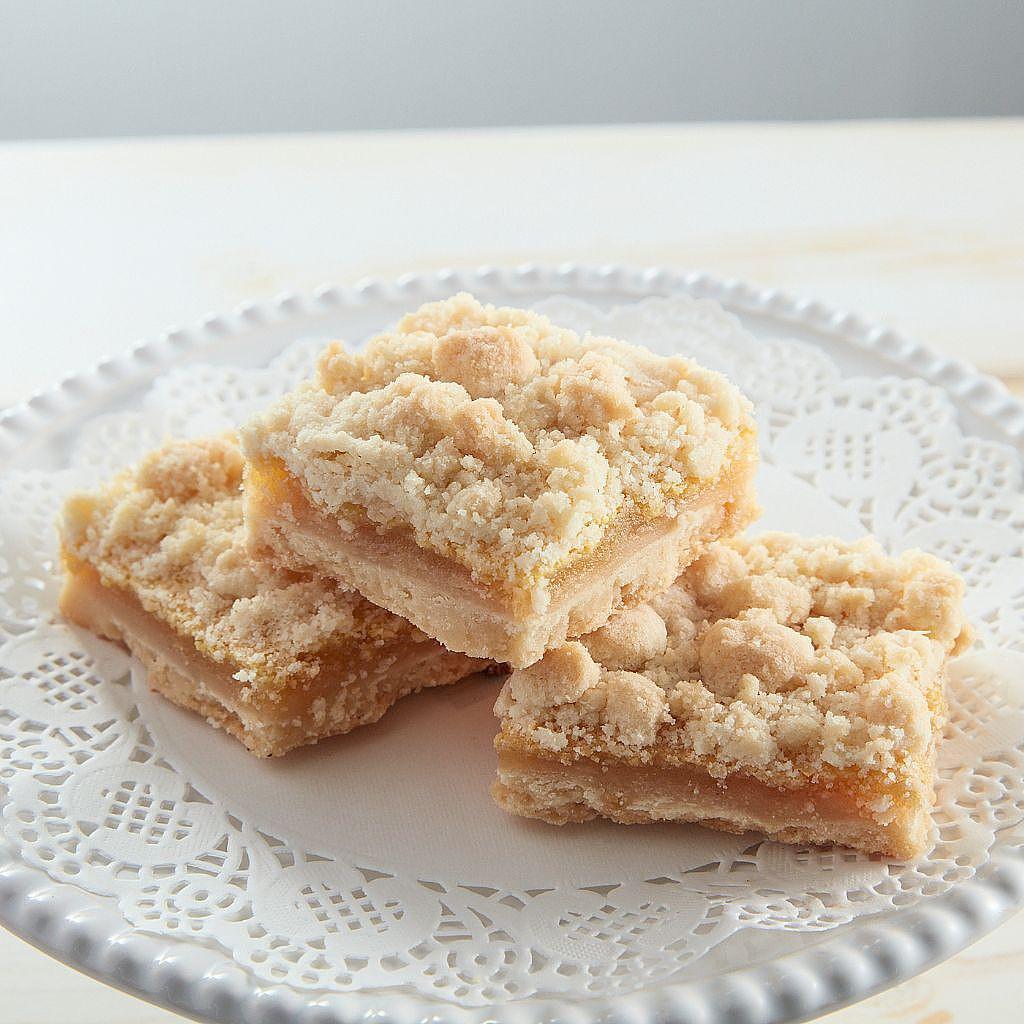 Lemon squares with crumb topping on a white doily plate