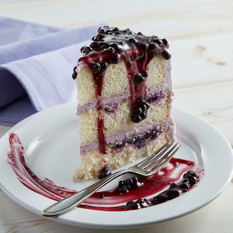 Slice of 9-inch lemon blueberry cake with berry glaze