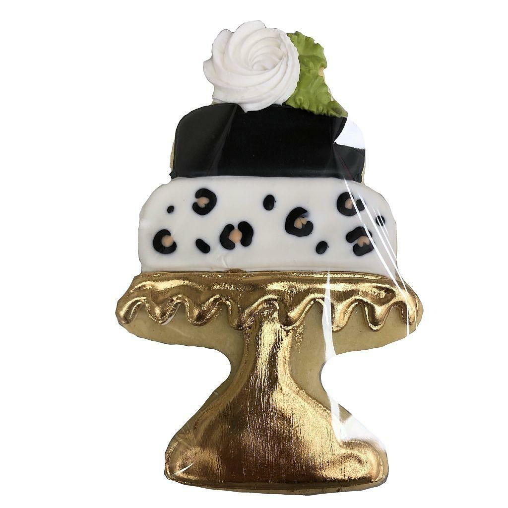 Leopard cake cookie on a gold stand with white frosting rose.