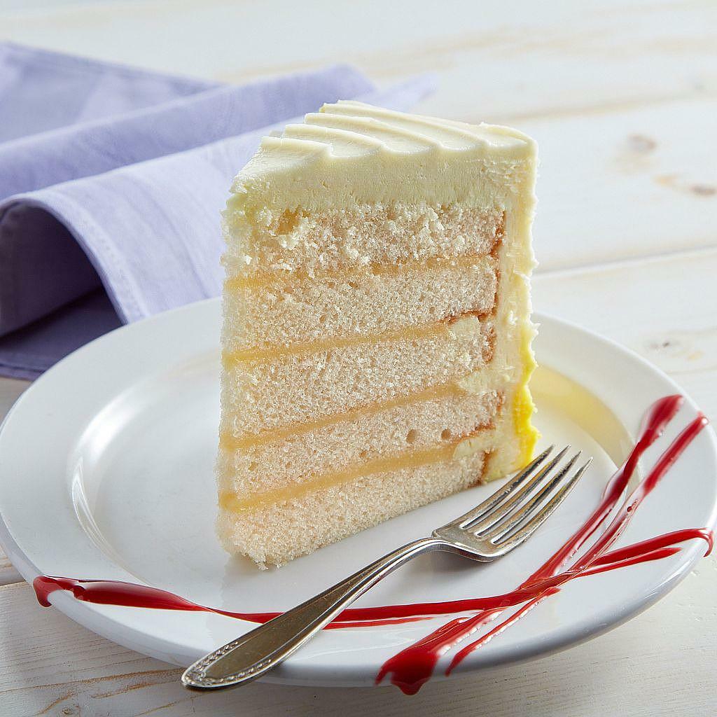 Luscious 9-inch lemon cake slice with white frosting on a plate.