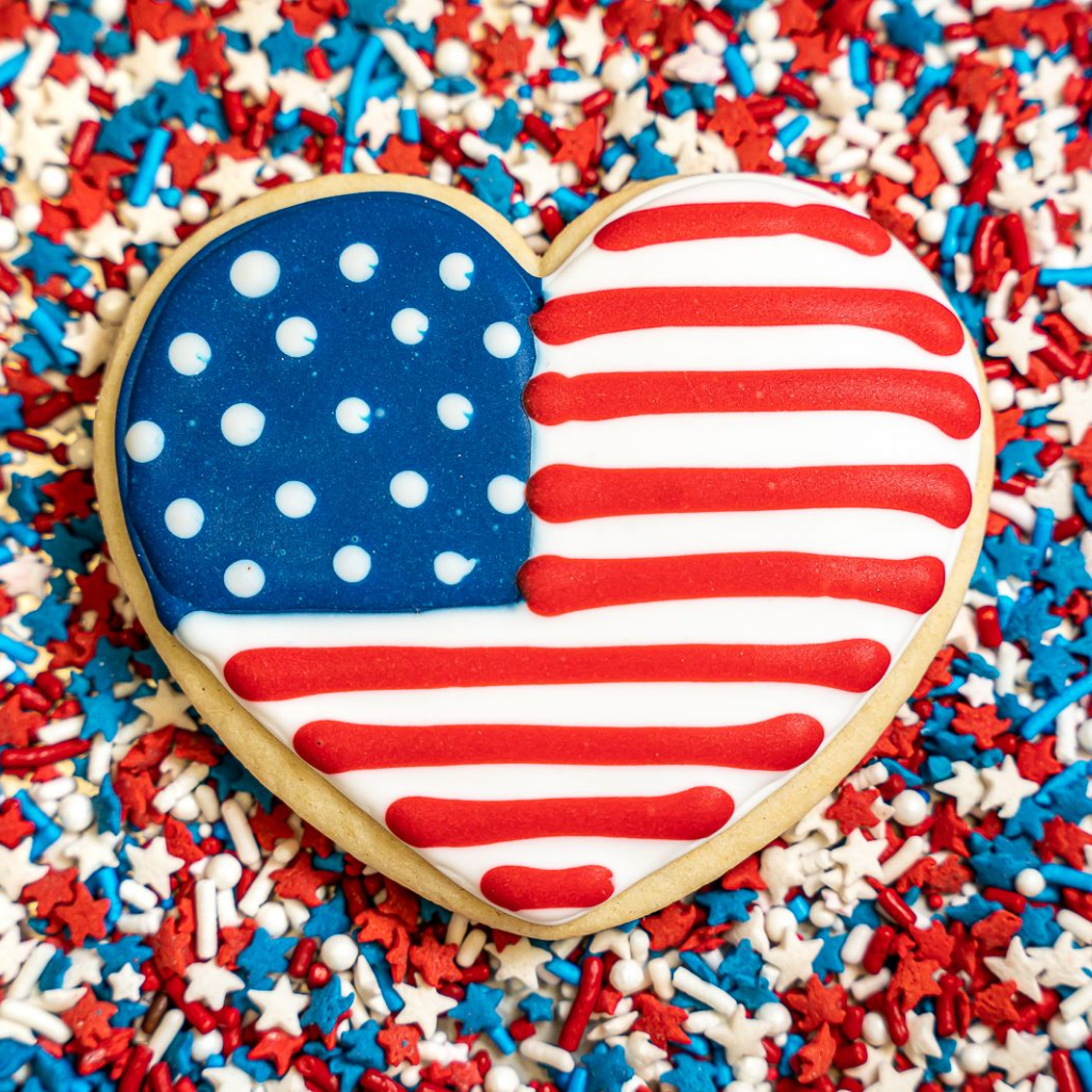 Heart-shaped Memorial Day cookie with flag icing on sprinkles.