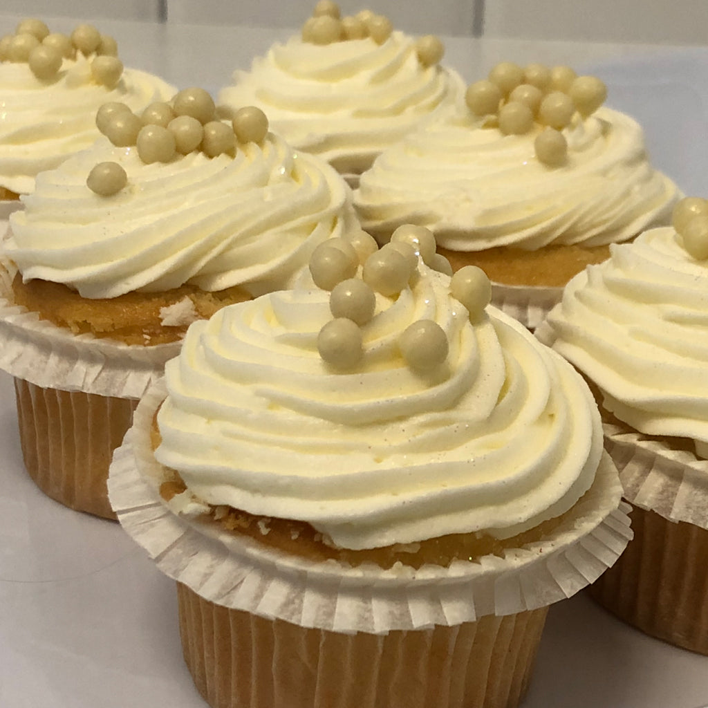 Mini vanilla cupcakes with white frosting and pearl sprinkles.