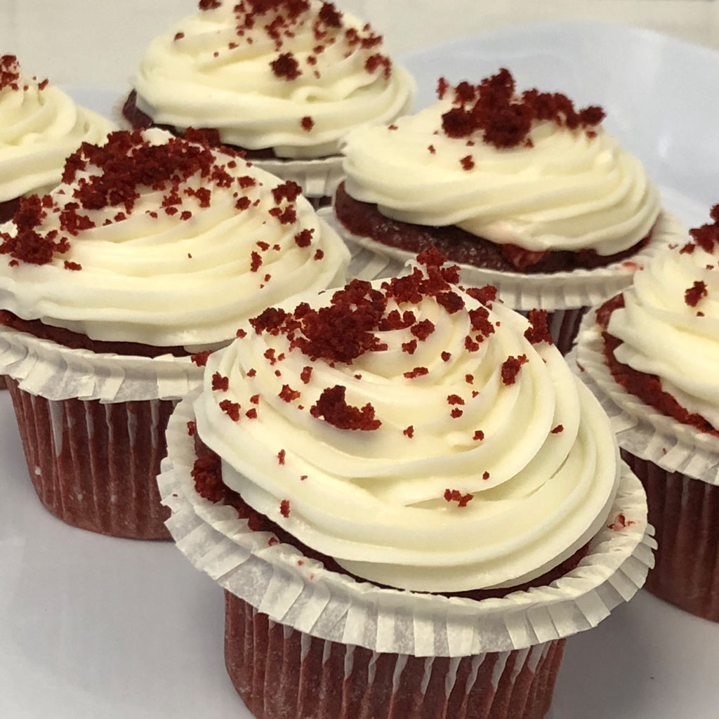 Mini red velvet cupcakes with white frosting and red crumbs.