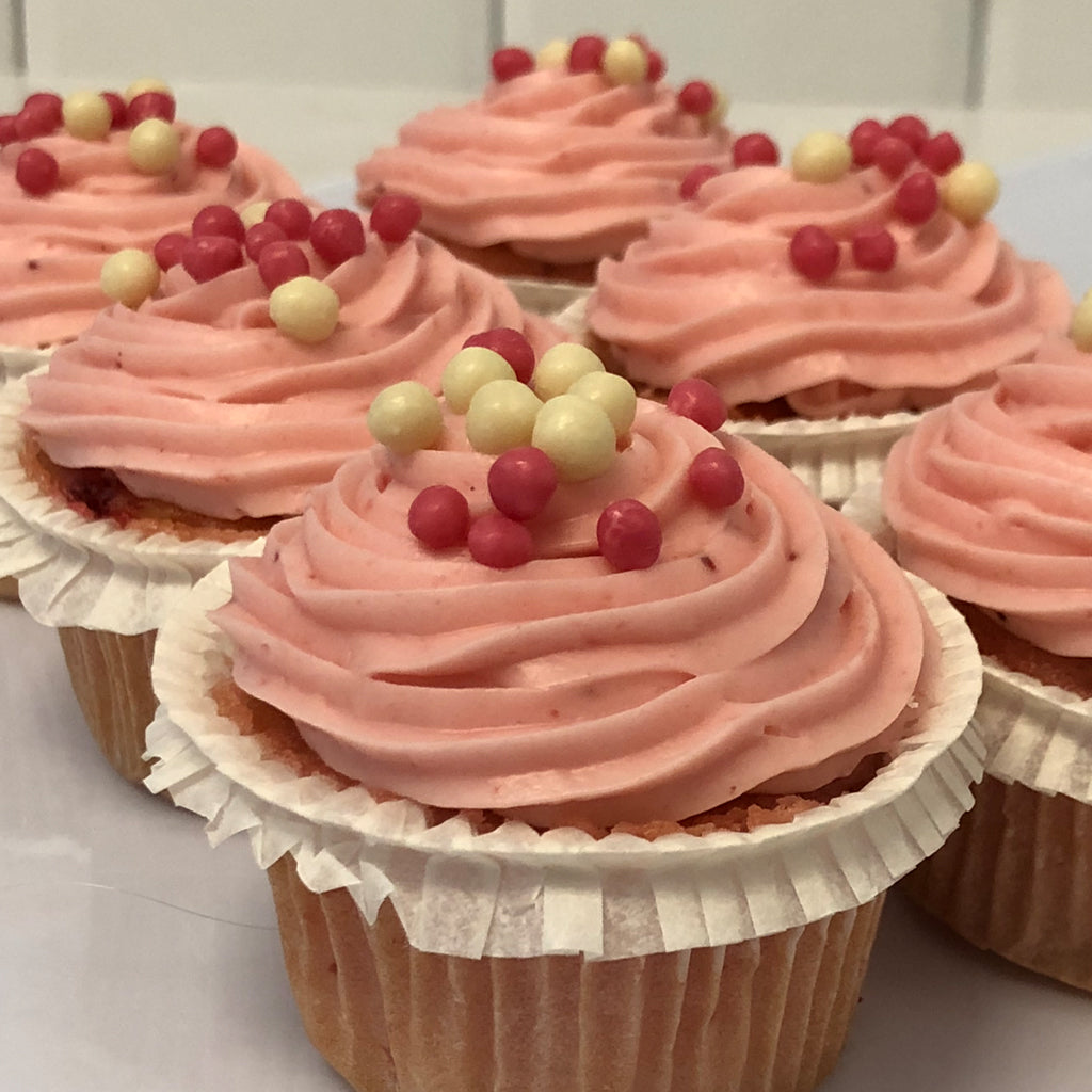Mini strawberry cupcakes with pink frosting and sprinkles.