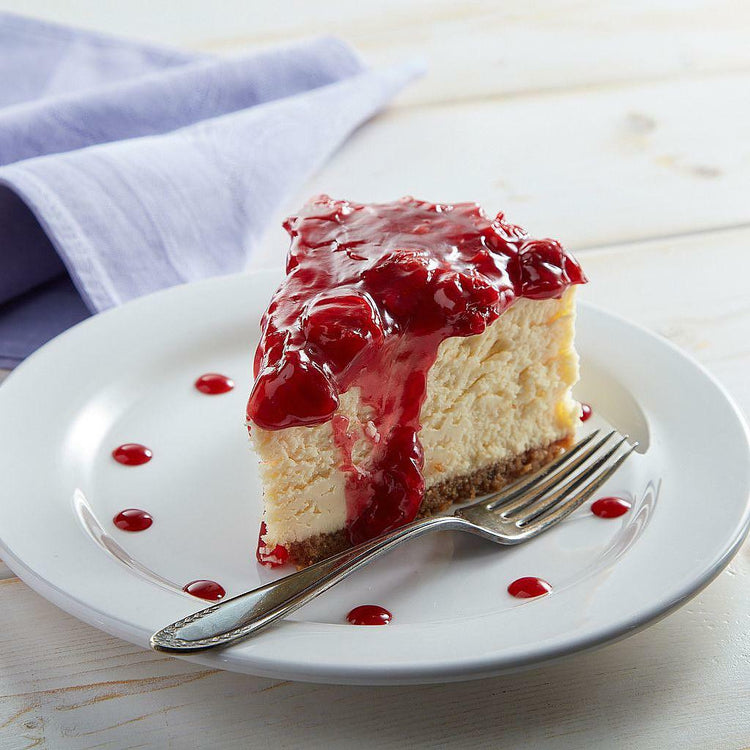 NY Cheesecake slice topped with cherry glaze on a white plate.