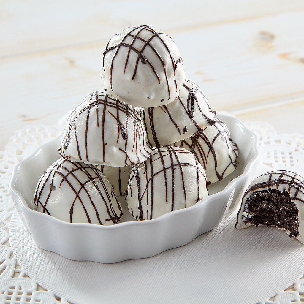 Oreo Truffles with white chocolate drizzle in a white dish