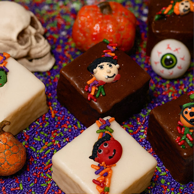 Halloween petit fours with spooky icing on purple sprinkles.