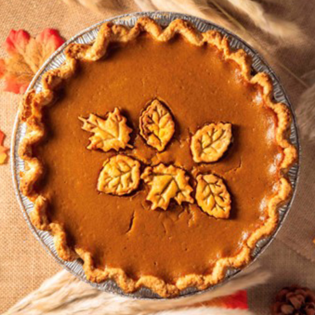 Rustic pumpkin pie topped with decorative pastry leaves.