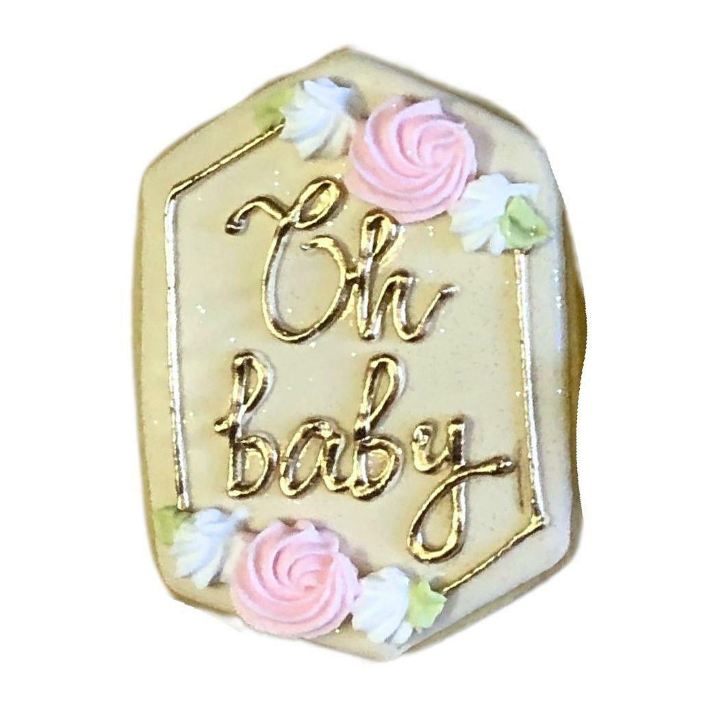 Pink and gold Oh Baby! plaque decorated with icing flowers.