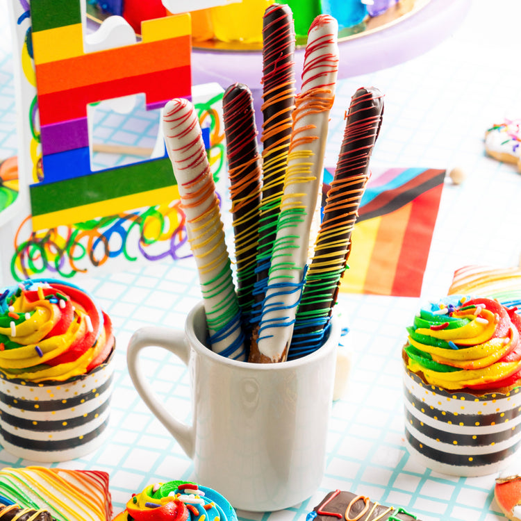 Pride Pretzels drizzled with rainbow icing in a white mug.