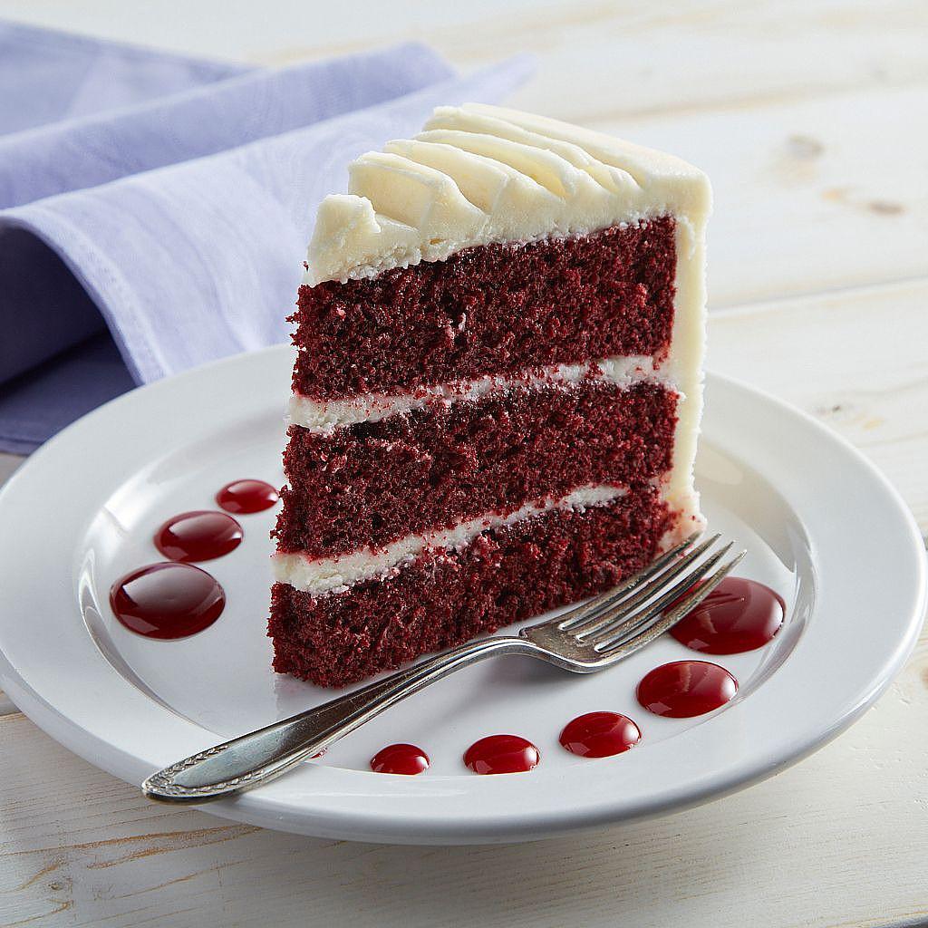 Slice of red velvet cake with cream cheese frosting on a plate