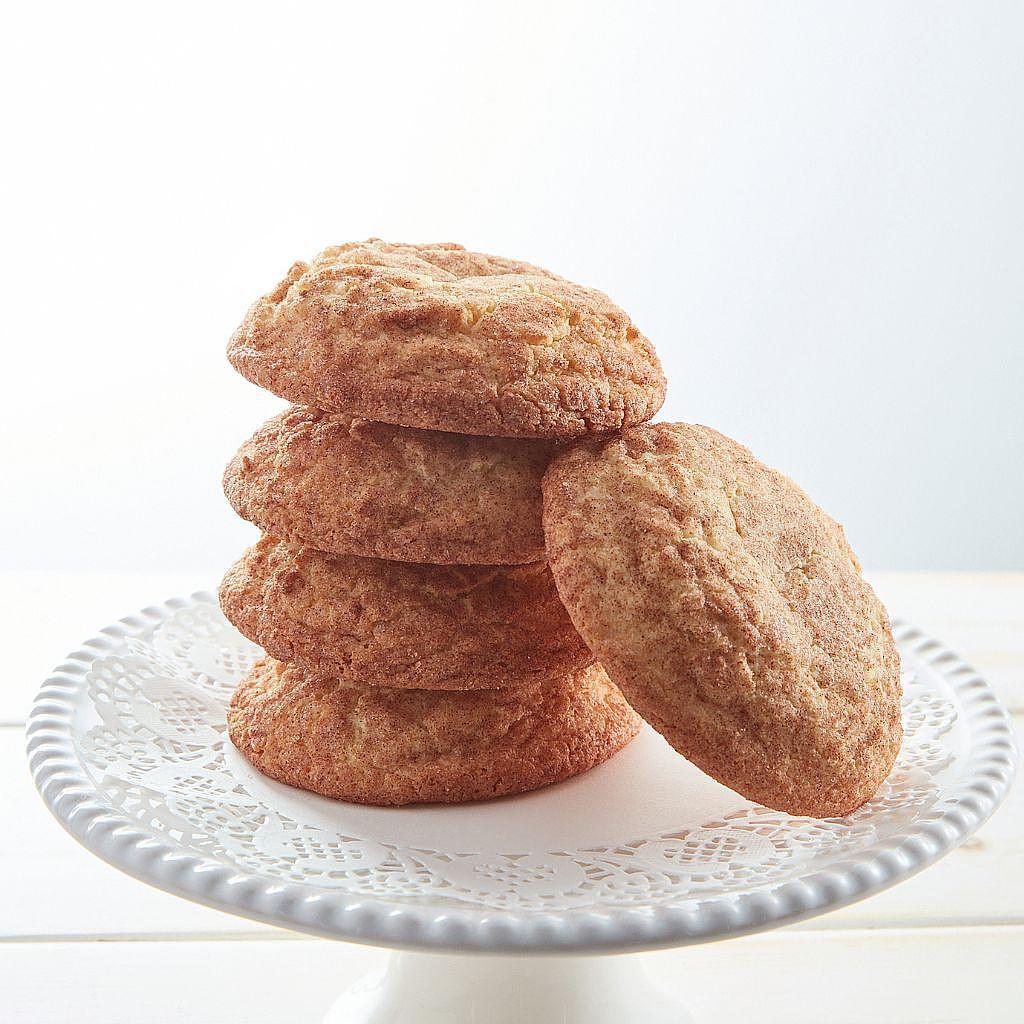 Stack of cinnamon-dusted snickerdoodles on a white cake stand